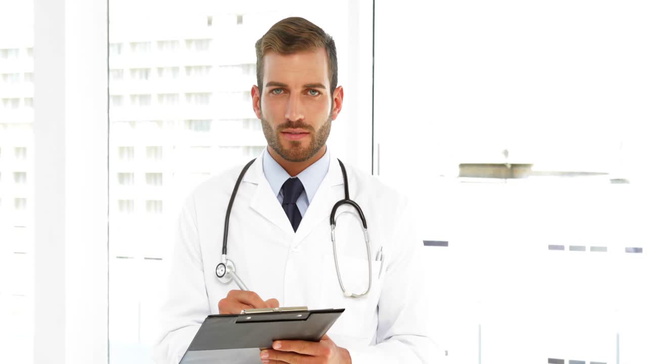Serious doctor writing on a clipboard