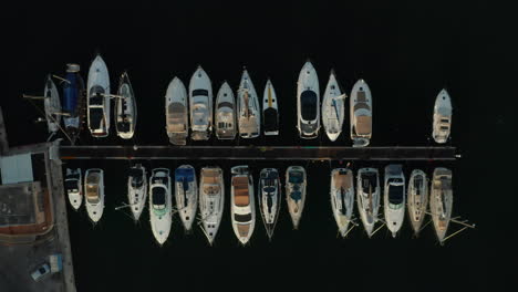 Birds-Eye-View-of-Sailboats-in-Harbour-with-black-water-background,-Aerial-Top-Down-View