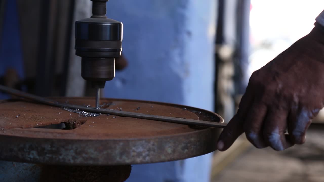 mano del hombre en el trabajo con un viejo taladro eléctrico oxidado en el laboratorio de la aldea sakhi saheli, rajasthan
