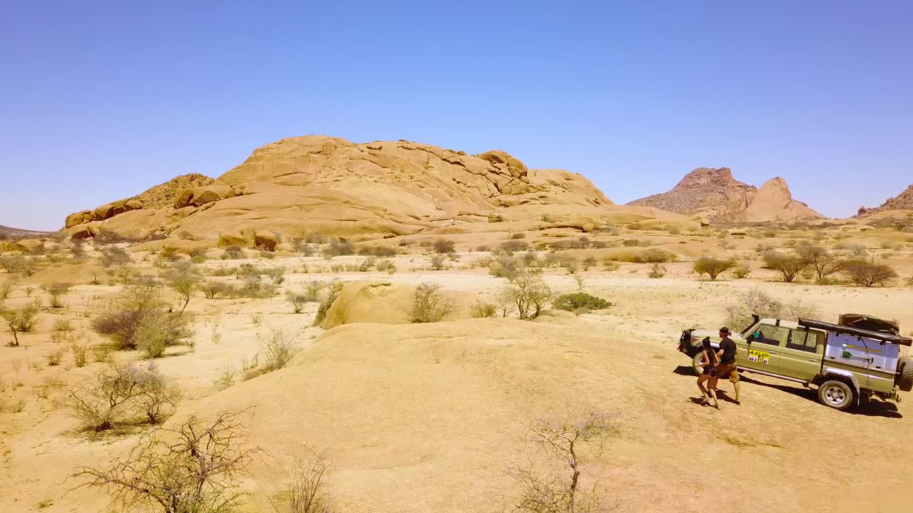 spitzkoppe namibia africa의 험준한 사막 풍경에서 4wd 사파리 지프 근처를 걷는 한 쌍의 공중
