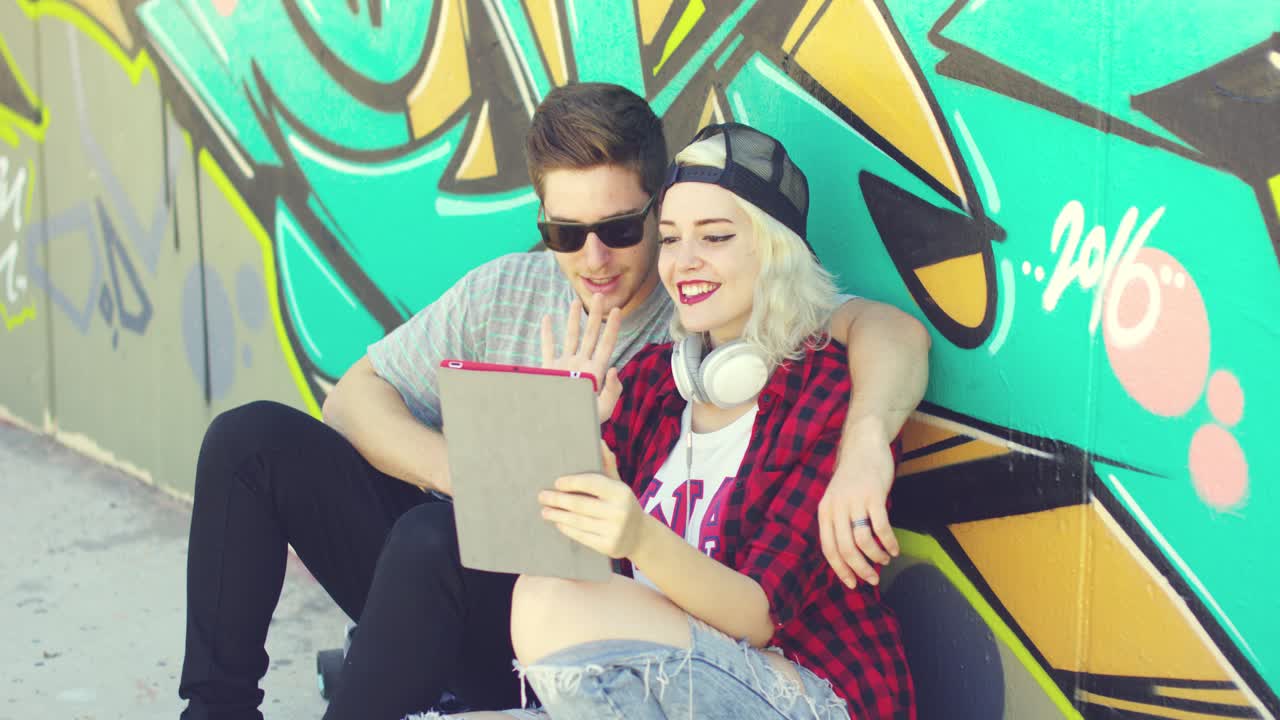 pareja joven hipster riendo revisando una tableta