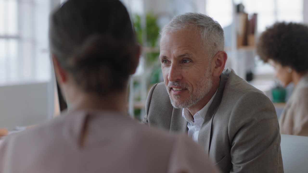 uomo d'affari maturo che chiacchiera con un tirocinante che discute di un colloquio di lavoro colleghi che conversano in ufficio che si godono il lavoro di squadra
