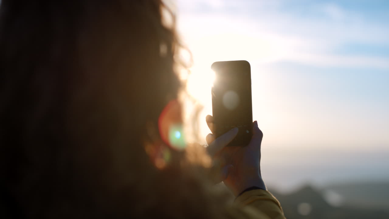 mujer tomando una foto del amanecer o la puesta del sol