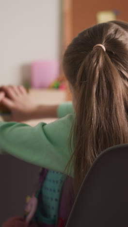 cute girl with long ponytails takes books stack out of schoolbag sitting in room. primary school pupil prepares for homework at home after classes