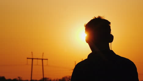 Teenager-In-Kopfhörern,-Die-Musik-Hören-Und-Einen-Wunderschönen-Sonnenuntergang-über-Dem-Stadtblick-Von-Behi-Betrachten