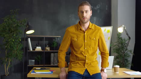 Young-Handsome-Man-In-Yellow-Shirt-With-Crossed-Hands-Looking-At-Camera-With-Serious-Face-In-The-Office-1