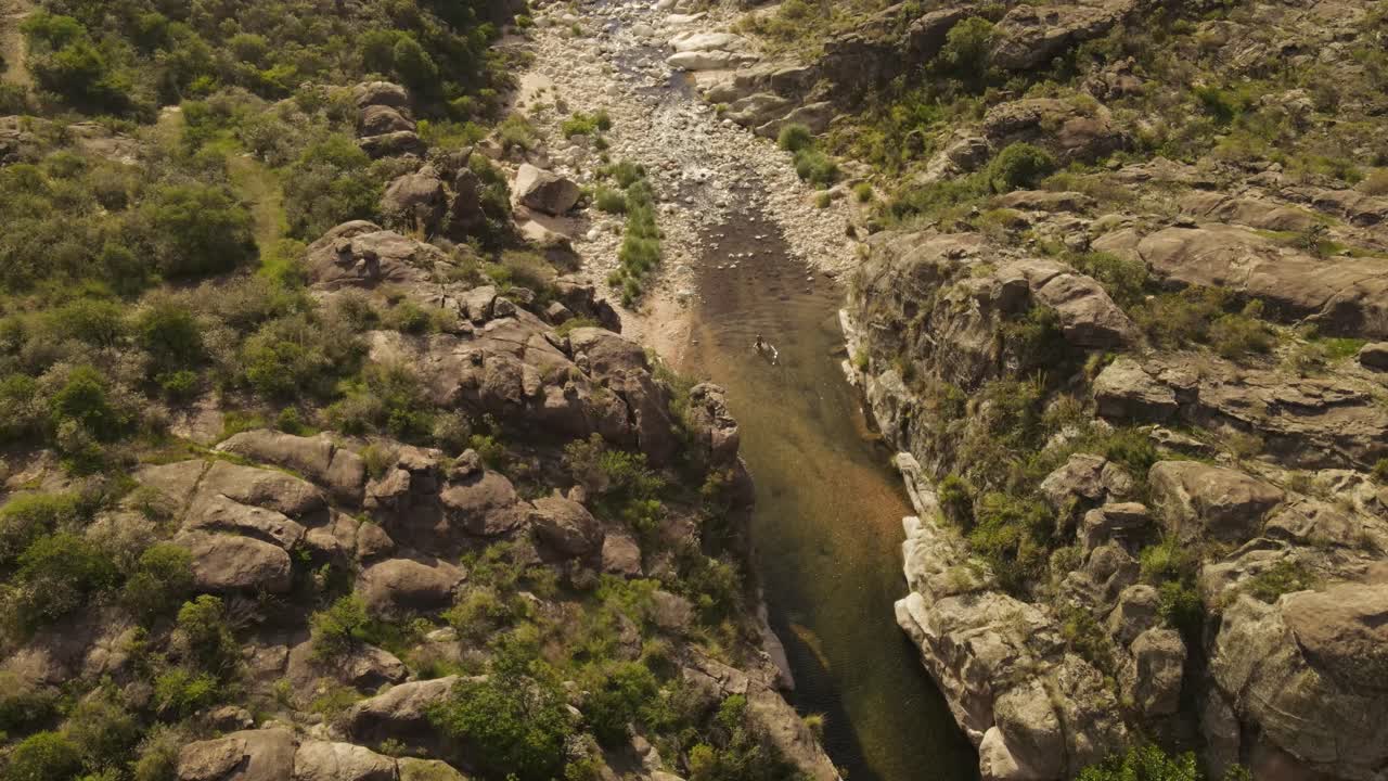 sobrevuelo aéreo persona caminando dentro del río rodeado por el paisaje escénico de argentina en un caluroso día de verano - enfriamiento dentro del agua durante la caminata