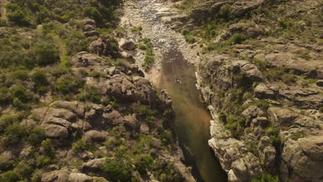 aerial flyover person walking inside river surrounded by scenic landscape of argentina on hot summer day - cooling inside water during hike