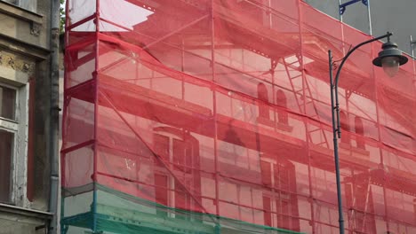 scaffolding with red netting over an old house. exterior view of building renovation