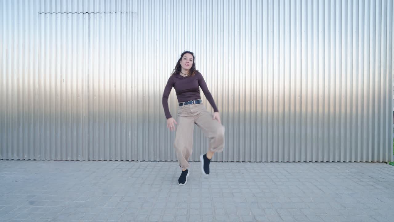 Young woman dancing freestyle in front of metal wall
