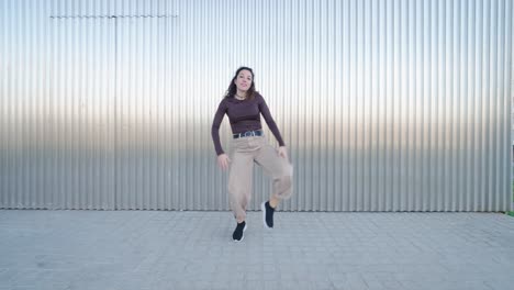 young woman dancing freestyle in front of metal wall