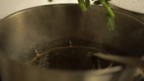 gros plan - chef mettant un brocoli cru dans une casserole d'eau chaude dans une cuisine de restaurant