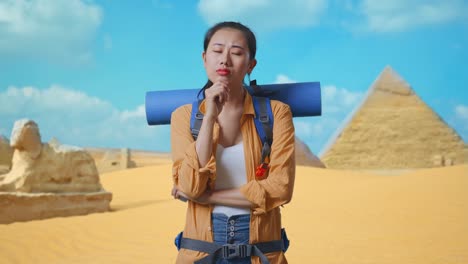 asian female hiker with mountaineering backpack thinking about something and looking around while traveling in pyramid of giza