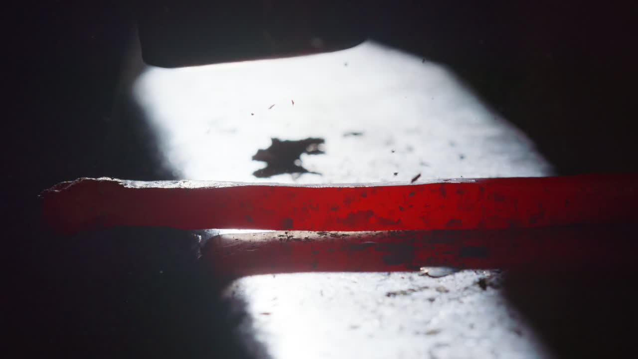 Backlit and closeup- a red hot iron is hammered on the anvil, slow motion