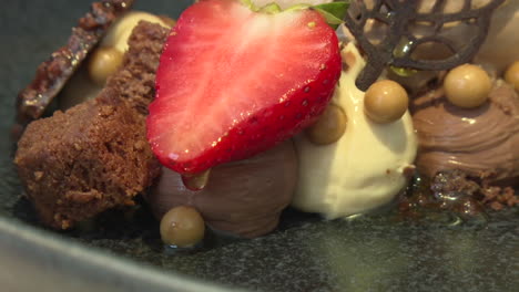 close-up of a plated dessert with chocolate, strawberry, and ice cream