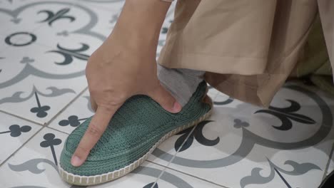 woman's hands wearing a pair of green knitted slippers