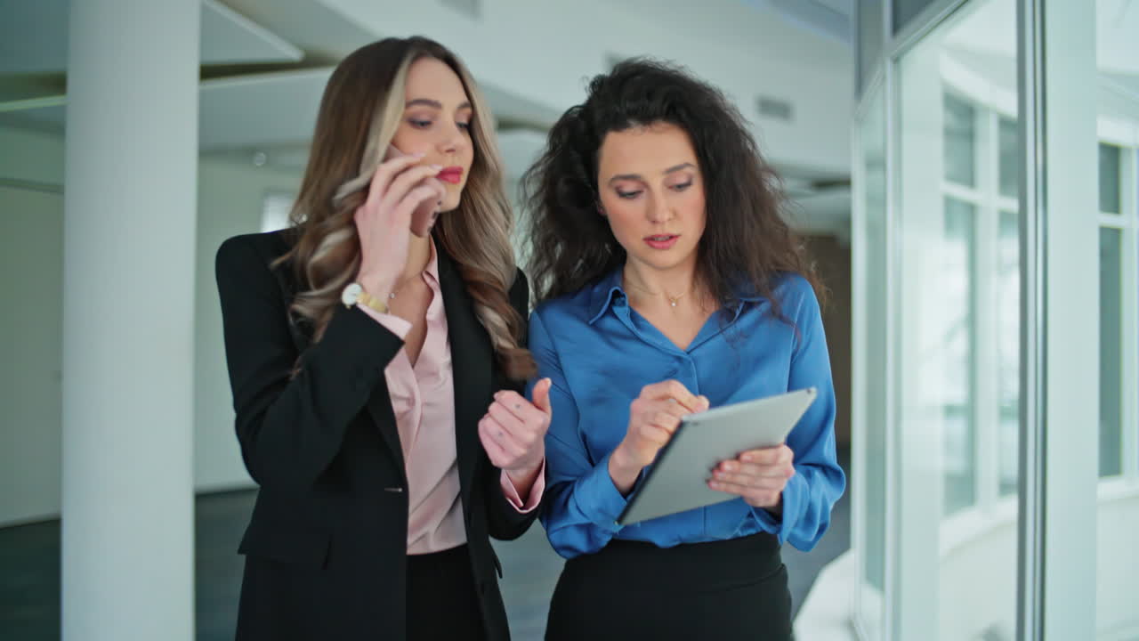 Mujeres profesionales usando teléfono y tableta. Gerentes en un espacio de trabajo moderno en primer plano.
