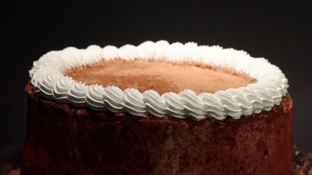 Detaljert nærbilde av kanelkake med krem på et roterende fat, søt, velsmakende og sunn, med svart bakgrunn i loop.