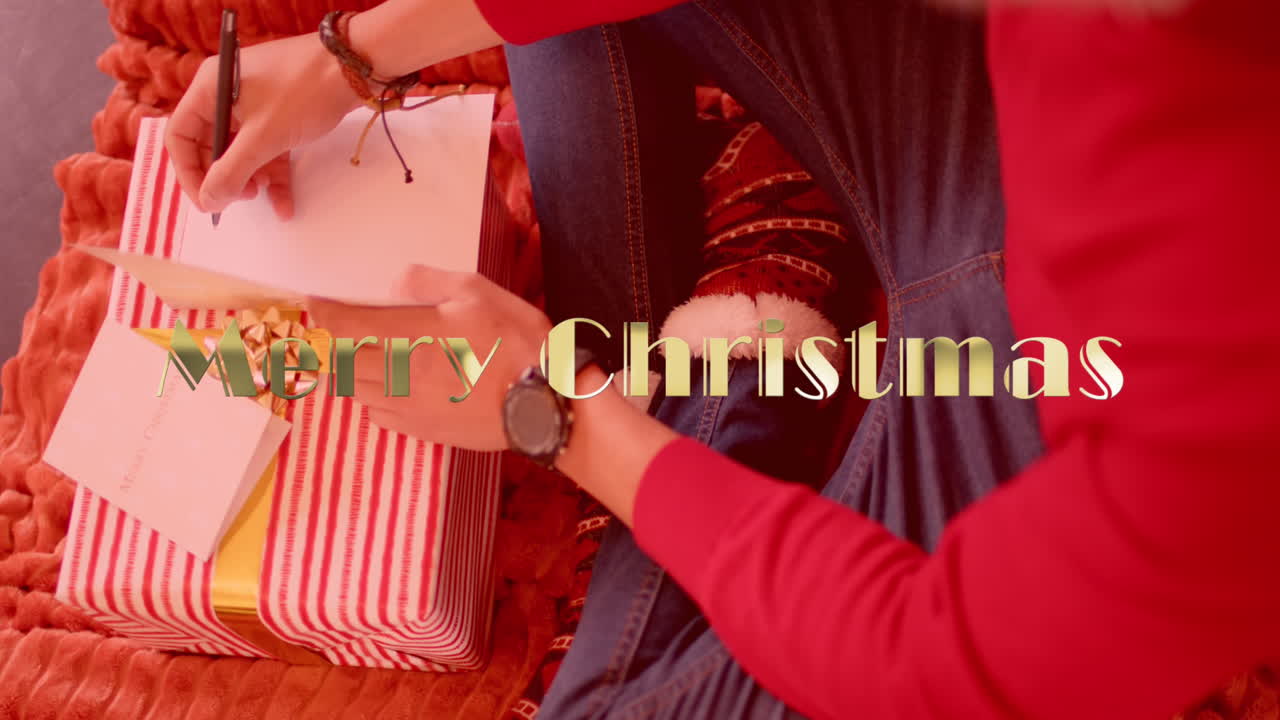 animación de felices vacaciones texto sobre hombre caucásico escribiendo tarjetas de navidad con regalos