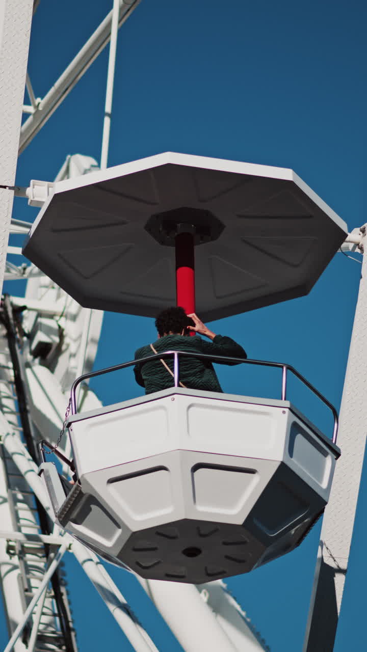 Close up of people in a cabin in a Ferris Wheel with the blue sky on the background. Vertical