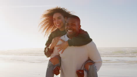 Hombre-Dando-Mujer-A-Cuestas-En-Vacaciones-De-Invierno-En-La-Playa