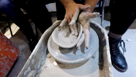 overhead close view of an african american hands spinning clay very sporadically while the mold begins to fall apart