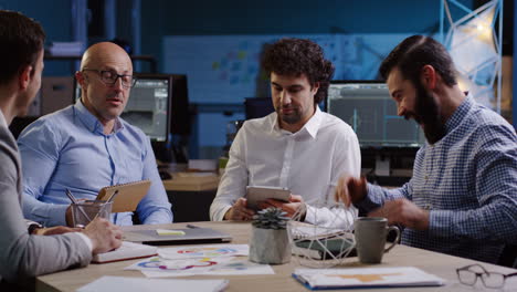 cuatro hombres de negocios sentados a la mesa y discutiendo sus planes futuros en la oficina