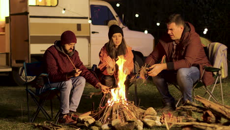 Girl-warming-up-her-hands-while-her-friend-making-the-fire-stronger