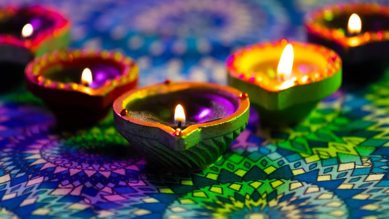 video de velas de diwali encendidas brillantes en una superficie con patrón de púrpura a verde