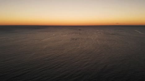 Drone-flying-above-sea-and-a-boat-in-the-background