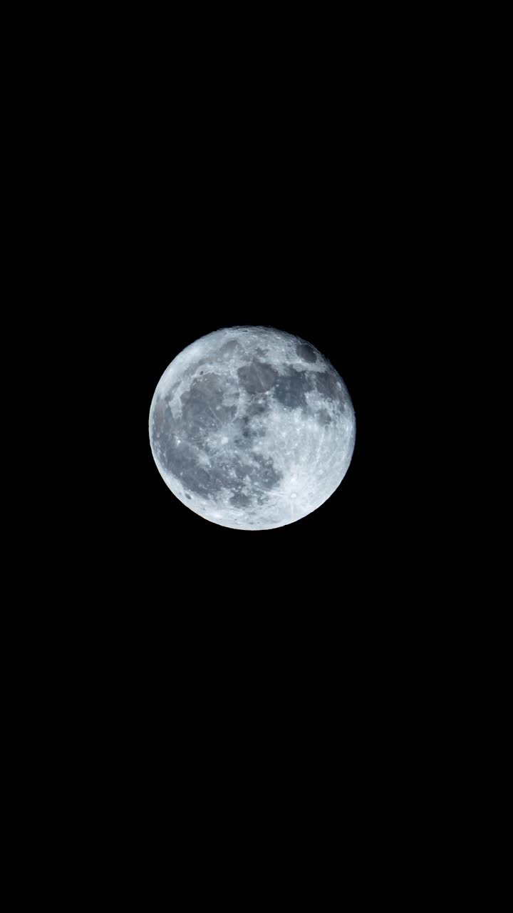 Full moon rising on a night with no clouds zoomed in to show detail - vertical timelapse