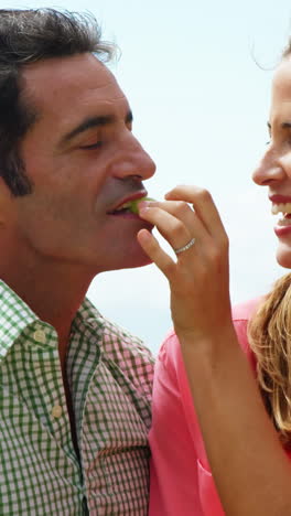 happy young woman feeding grape to man in field