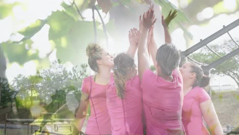 Animation-of-leaves-over-diverse-women-at-obstacle-course-high-fiving