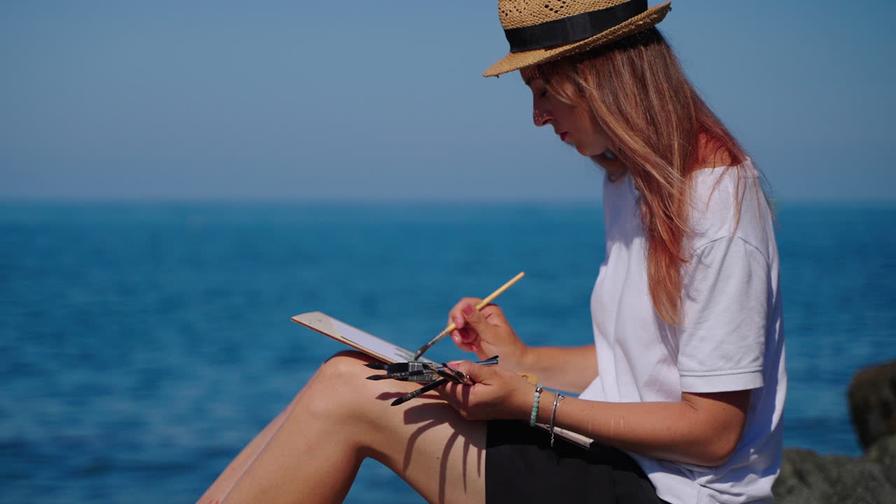 mujer pintando paisajes marinos en la playa