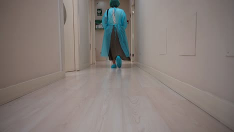 person in protective clothing walking down a hospital hallway