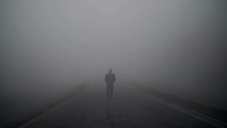 solitary man traversing desolate road, enveloped by dense fog, embodying mysterious journey through ethereal, moody landscape with haunting atmospheric tension