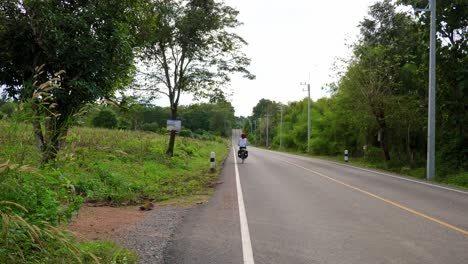 Mujer-Sola-En-Bicicleta-Por-Una-Carretera-Asfaltada-En-Una-Carretera-Rural-Sin-Tráfico,-Tailandia