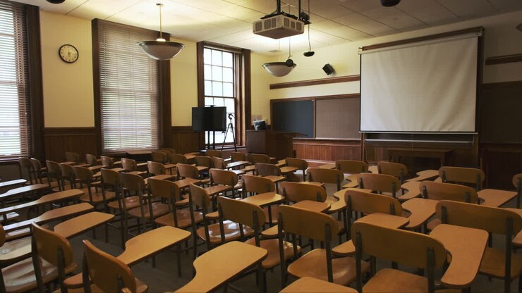 Deserted classroom full of empty vintage writing chairs