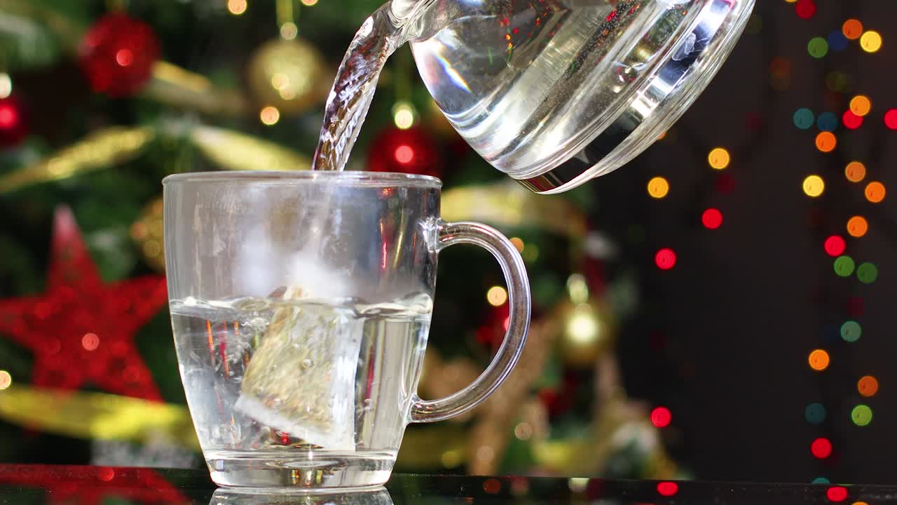 차와 크리스마스 트리 뒤에 컵에 뜨거운 물을 부어