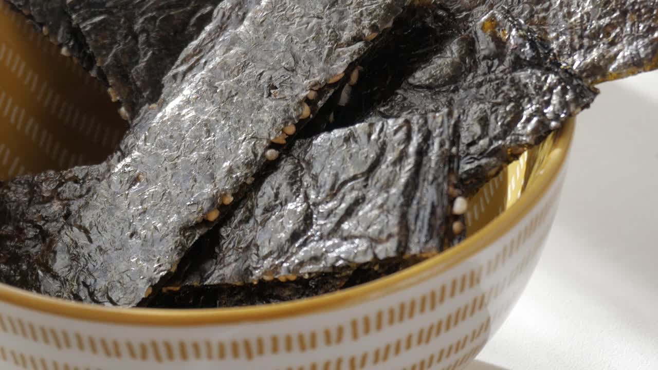 Crispy seaweed snack in a bowl with sesame seeds, shot in soft natural daylight