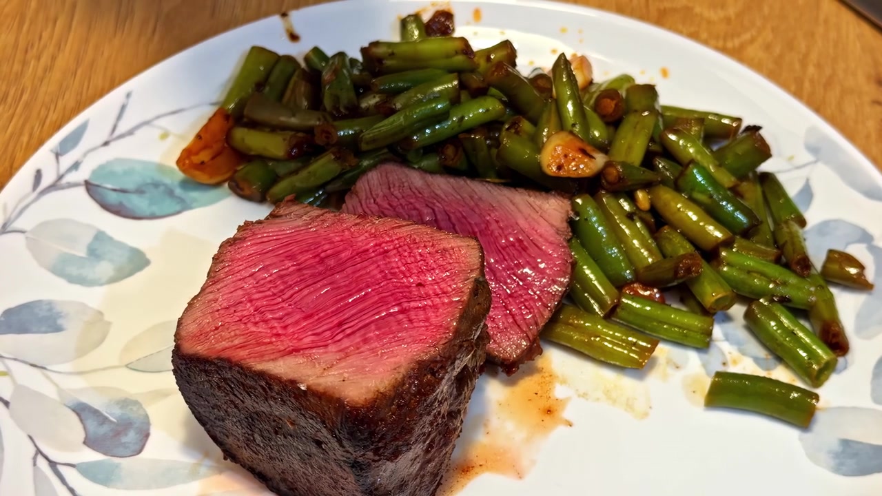Perfekt gegartes Steak zusammen mit sautierten grünen Bohnen, Rindfleisch medium rare, gehobenes Restaurant.
