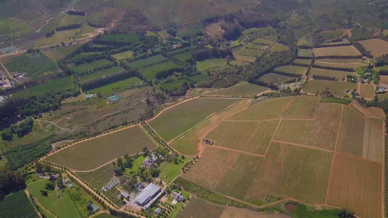 disparo de drones de gran angular inclinándose hacia tierras de cultivo en el valle de banhoek