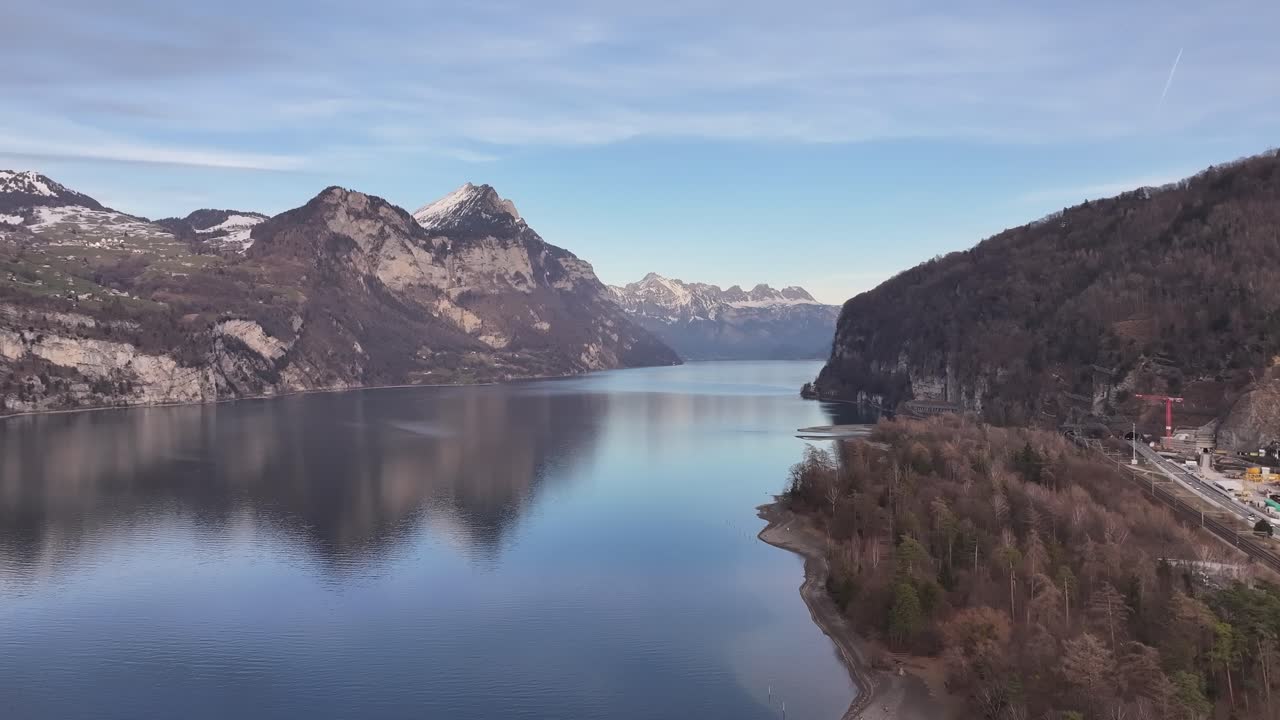 A breathtaking view of Walensee near Weesen, Switzerland, with the calm lake reflecting the snow-capped mountains and the surrounding forests, creating a tranquil alpine landscape.