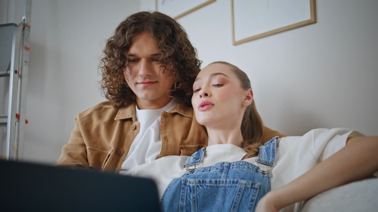 Bonding couple watching laptop on comfortable home couch closeup. Married pair
