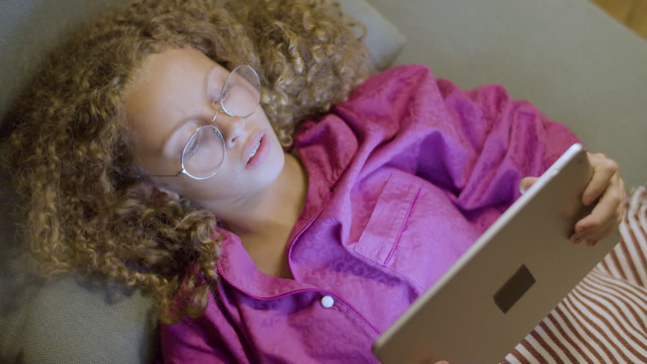 침대에 누워 태블릿 게임을 하는 어린 소녀의 근접 촬영