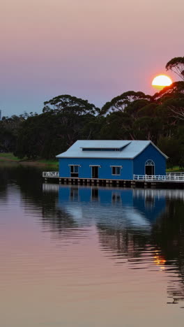 blue boat house on a lake at sunset