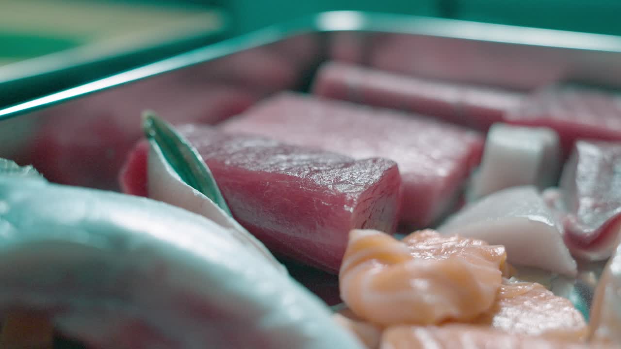 A static up-close shot showcasing a variety of raw fish, highlighting their fresh cuts, textures, and vibrant colors, perfect for sushi preparation or other seafood dishes.