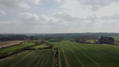 Un-Dron-En-Ascenso-Disparó-Sobre-Un-Campo-Con-Un-Arroyo-Rodando-Por-El-Medio-En-Egerton,-Inglaterra,-Con-El-Río-Stour