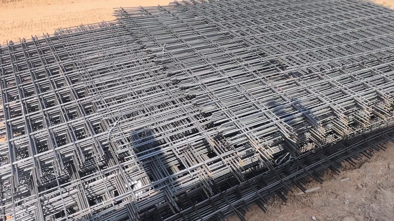 Steel BRC wire mesh laid on a construction site. Used for workers prepare the reinforcement for a concrete floor slab. This mesh ensures structural integrity and durability.