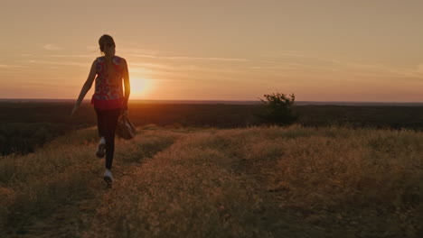 a cheerful child runs and waves his back pack during sunset